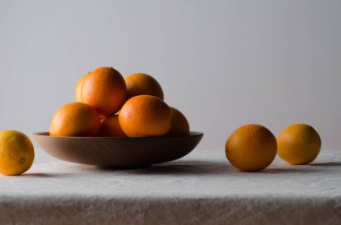 Portakal beyaz keten masa örtüsü üzerinde ahşap bir kasede.