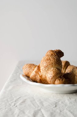 Beyaz keten masa örtüsü üzerinde taze kruvasanlar.