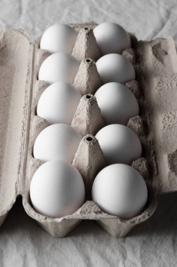 Bir yumurta kartonu beyaz yumurtalar. Beyaz keten masa örtüsü arka plan.