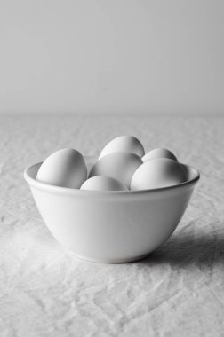 Beyaz yumurta beyaz bir kase. Beyaz keten masa örtüsü arka plan.