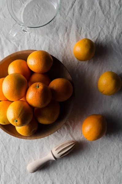 Portakal beyaz keten masa örtüsü üzerinde ahşap bir kasede.