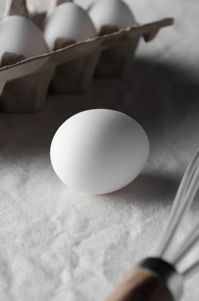 Close-up of white egg on a white linen tablecloth background.