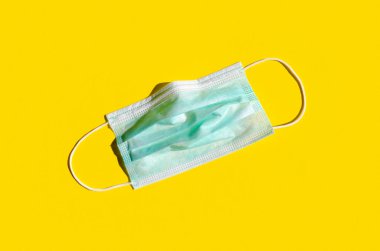 Parlak sarı arka planda tıbbi ya da cerrahi yüz maskesi.