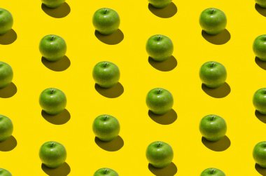 Sarı arka planda yeşil elma deseni. Sert gölgeler.