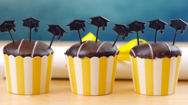 Cap şapka toppers ile sarı ve mavi tema mezuniyet partisi cupcakes.