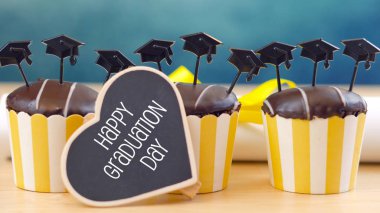 Yellow and blue theme graduation party cupcakes with cap hats toppers. clipart