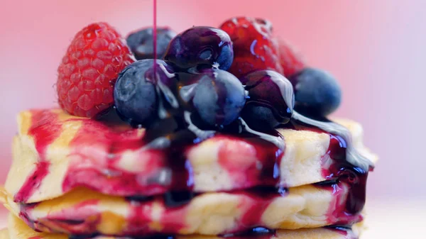 Pancakes with berries and drizzled with blueberry maple syrup, macro closeup. — Stock Photo, Image