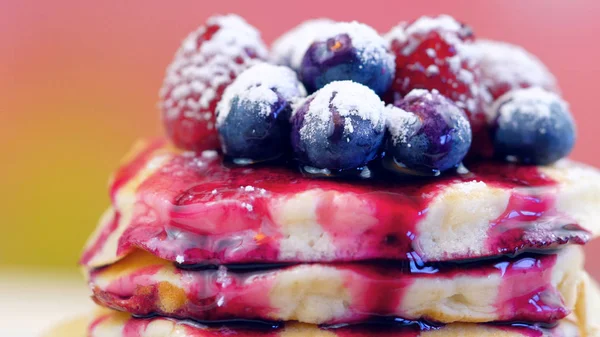 Pancakes with berries and drizzled with blueberry maple syrup, macro closeup. — Stock Photo, Image