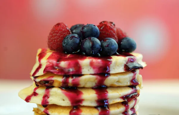 Pancakes with berries and drizzled with blueberry maple syrup, macro closeup. — Stock Photo, Image