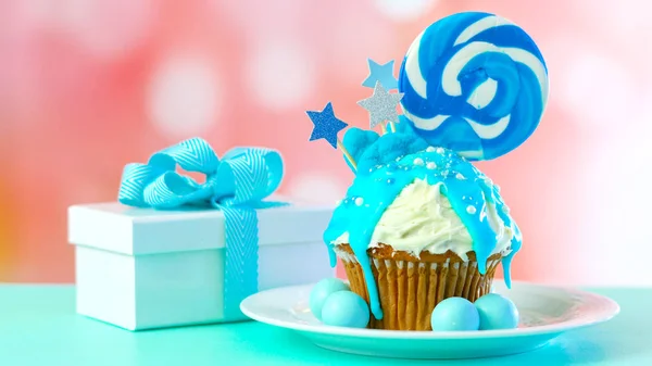 Blue novelty cupcake decorated with candy and large lollipops. — Stock Photo, Image