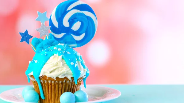 Blue novelty cupcake decorated with candy and large lollipops. — Stock Photo, Image