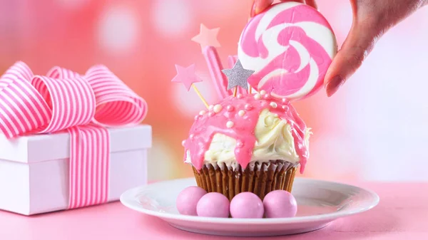 Розовый кекс, украшенный конфетами и большим леденцом . — стоковое фото