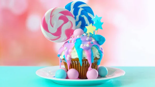 Pink and blue novelty cupcake decorated with candy and large lollipops. — Stock Photo, Image