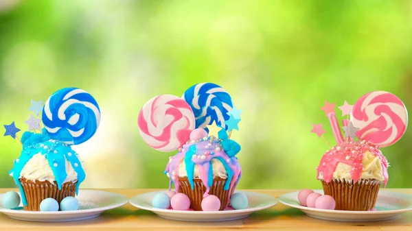 Rosa och blå nyhet cupcakes dekorerade med lollipop mot trädgården bakgrund — Stockfoto