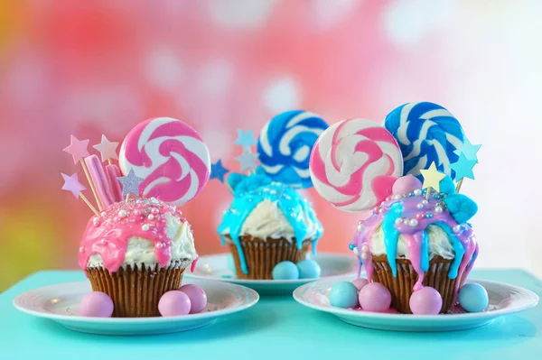 Tres cupcakes de novedad rosa y azul decorados con dulces y piruletas grandes . —  Fotos de Stock