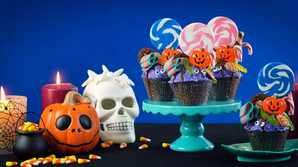 Halloween candyland drip cake style cupcakes with candy on blue background. — Stock Photo, Image