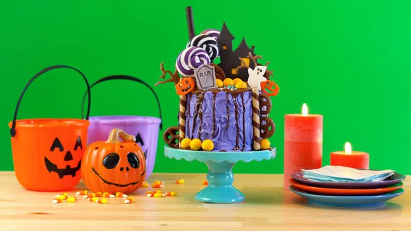 On trend Halloween candyland novelty drip cake against green background. — Stock Photo, Image