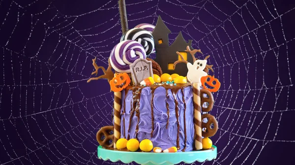On trend Halloween candyland novelty drip cake in colorful purple party setting.