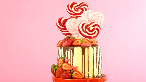 Valentines Day candyland drip cake decorated with heart shaped lollipops.