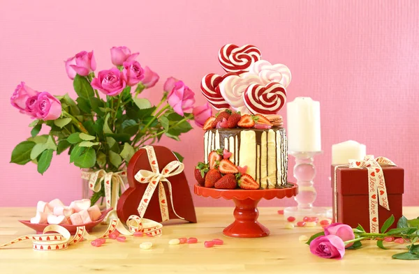 Valentines Day candyland drip cake decorated with heart shaped lollipops. — Stock Photo, Image