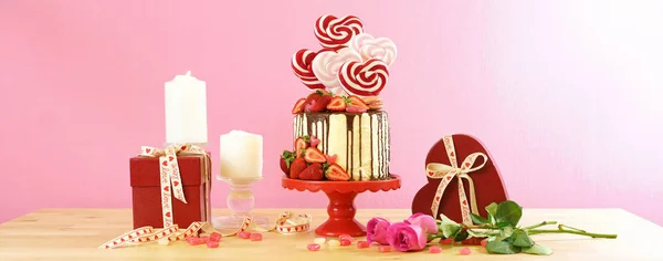 Valentines Day candyland drip cake decorated with heart shaped lollipops. — Stock Photo, Image