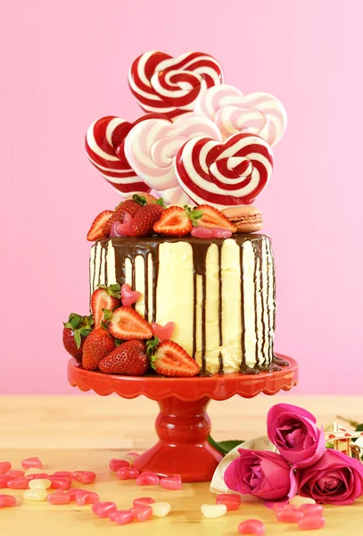 Día de San Valentín Candyland pastel de goteo decorado con piruletas en forma de corazón . —  Fotos de Stock