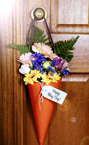 Gelukkig May Day gift van bloemen op deur met lens flare. — Stockfoto