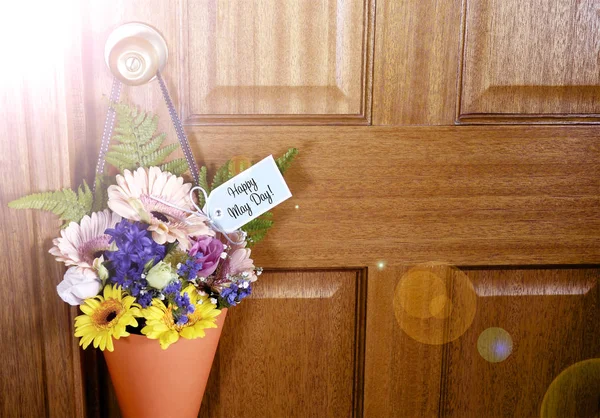 Happy May Day gift of flowers on door with lens flare. — Stock Photo, Image