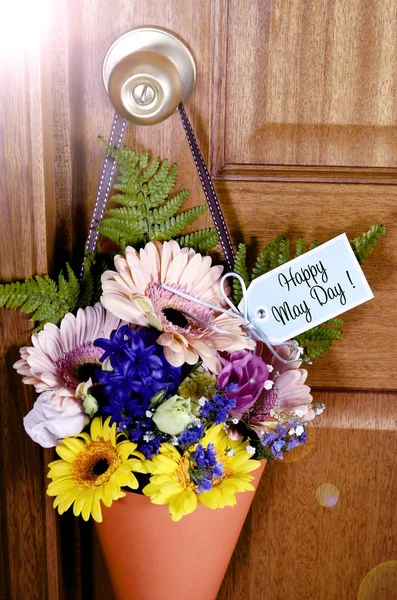 レンズ フレアのドア 木製のドア ハンドルからぶら下がっているオレンジ色のコーンの春の花の幸せのメーデーの伝統的な贈り物 — ストック写真