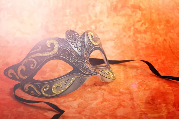 Mardi Gras mask on orange background with lens flare. — Stock Photo, Image