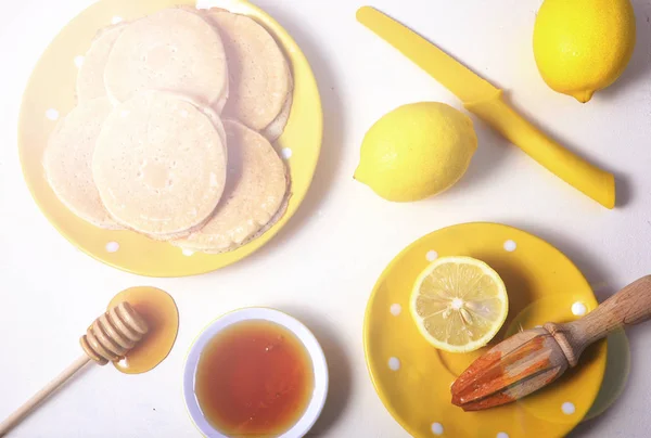 Shrove Tuesday pancakes, honey and lemons, with lens flare. — Stock Photo, Image