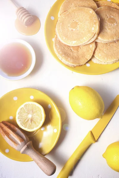 Shrove Tuesday pancakes, honey and lemons, with lens flare. — Stock Photo, Image
