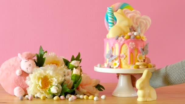 Easter candyland drip cake with white chocolate bunny in party table setting. — Stock Video