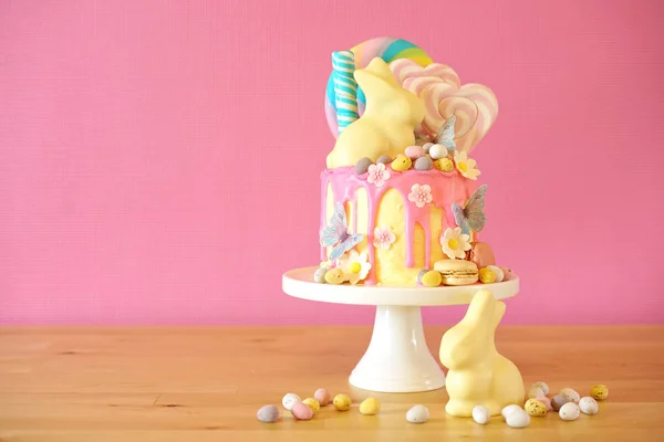 Bolo de gotejamento de terra de doces de Páscoa decorado com pirulitos e coelho branco . — Fotografia de Stock