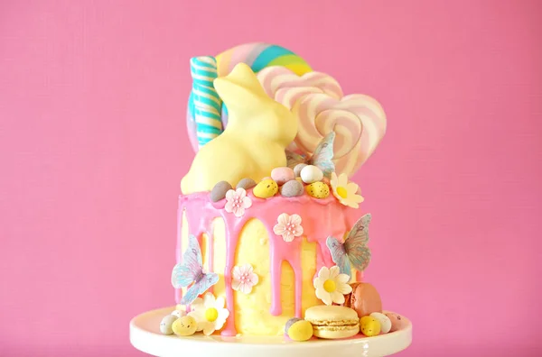 Easter candy land drip cake decorated with lollipops and white bunny. — Stock Photo, Image