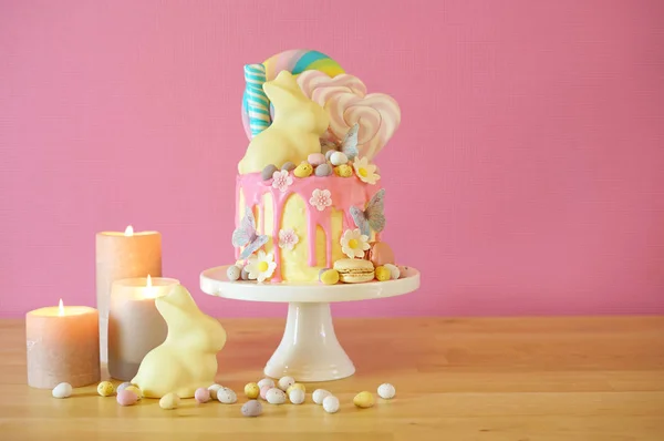 Easter candy land drip cake decorated with lollipops and white bunny. — Stock Photo, Image