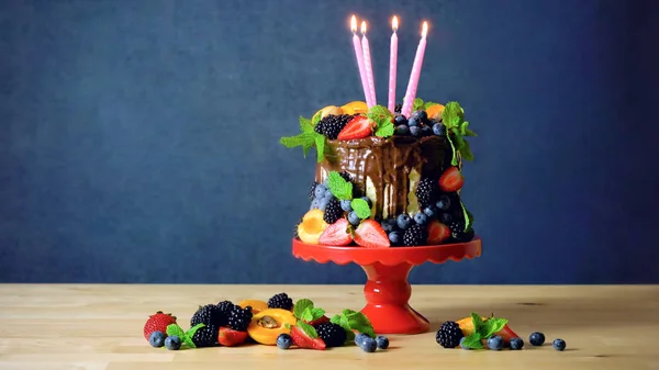 Delicious chocolate drip cake decorated with fresh seasonal fruit and berries. — Stock Photo, Image