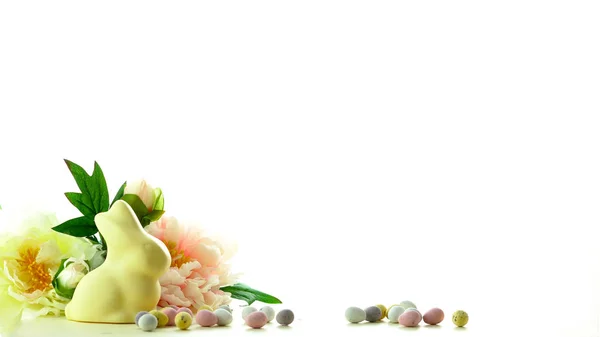 Pasen achtergrond met witte chocolade paashaas, eieren en lente bloemen grens. — Stockfoto