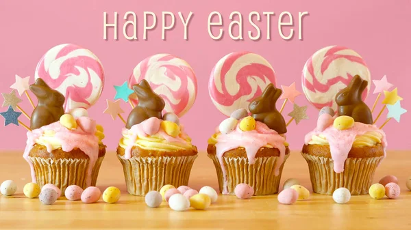 Dulces de Pascua tierra goteo cupcakes con conejitos de chocolate y saludo de texto . —  Fotos de Stock