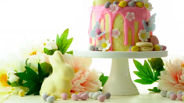 Pasen candyland druppelen cake met witte chocolade paashaas op witte achtergrond. — Stockvideo