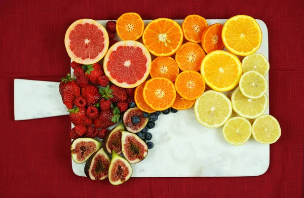 Colorful fruit platter assembly on white marble board with copy space.