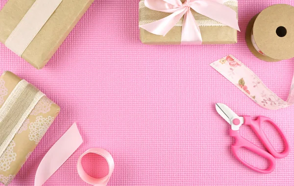 Gifts wrapped in kraft paper and pink ribbons overhead flatlay. — Stock Photo, Image