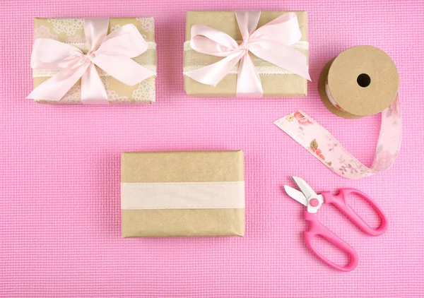 Ajándékok csomagolva Kraft papír és rózsaszín szalagok felső flatlay. — Stock Fotó