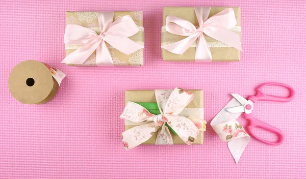 Geschenke eingewickelt in Kraftpapier und rosa Schleifen über dem Kopf. — Stockfoto