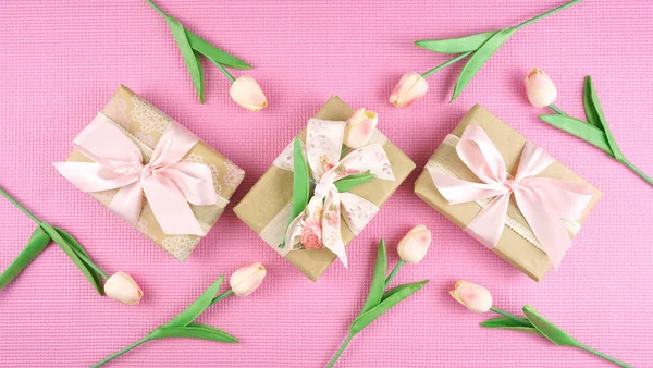 Geschenken verpakt in Kraft papier en roze linten overhead flatlay. — Stockfoto