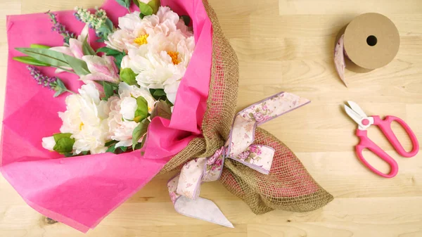 Flores envoltas em tecido rosa e tendência moderna hessiana embrulhando flatlay . — Fotografia de Stock