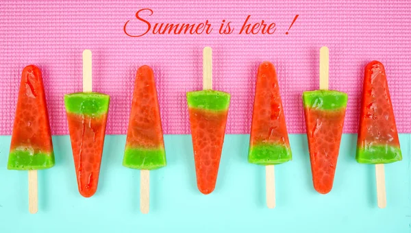 Watermelon flavored summer ice cream popsicles on pink and blue background.