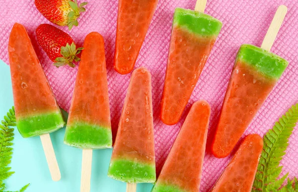 Watermelon flavored summer ice cream popsicles on pink and blue background.