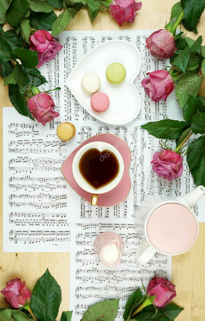 Feminine desk or workspace coffee break time flatlay with sheet music and roses.