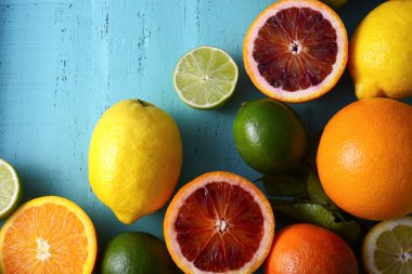 Mavi ahşap masada karışık renkli Narenciye meyve.